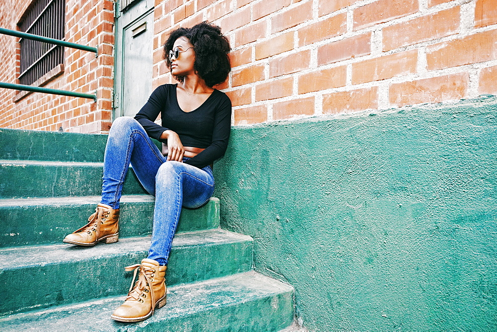 Black woman sitting on staircase outdoors