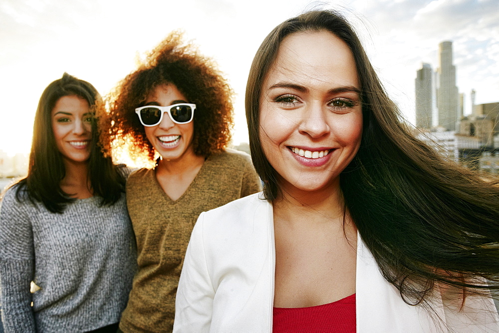 Portrait of smiling women on urban rooftop at sunset