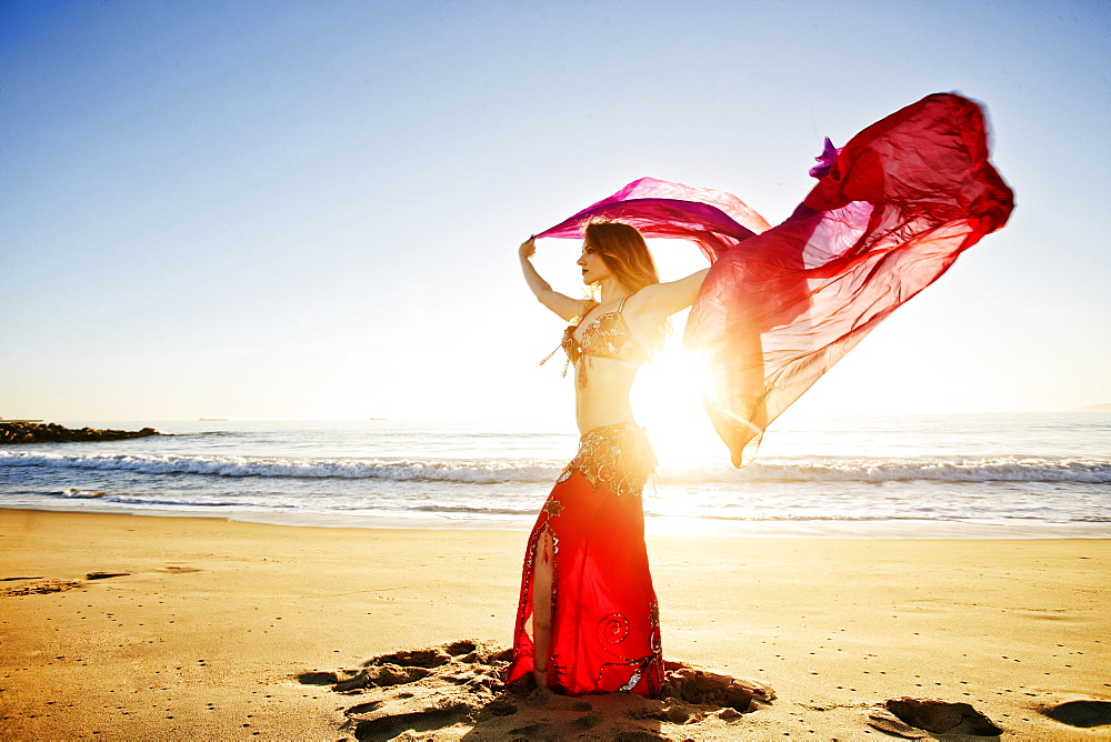 Caucasian belly dancer holding scarf on beach