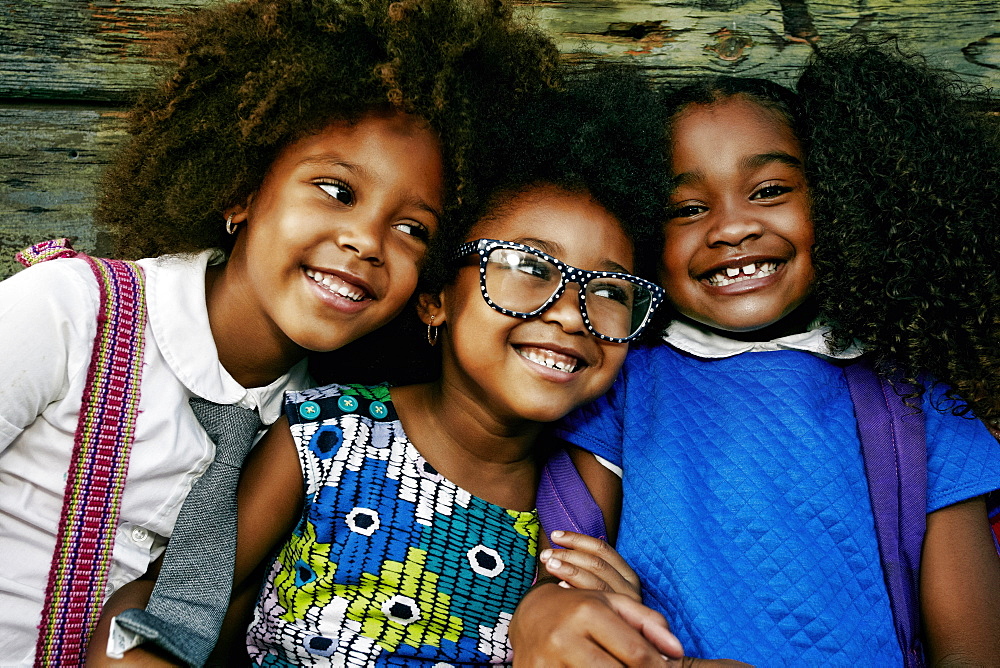 Portrait of smiling girls near wooden wall