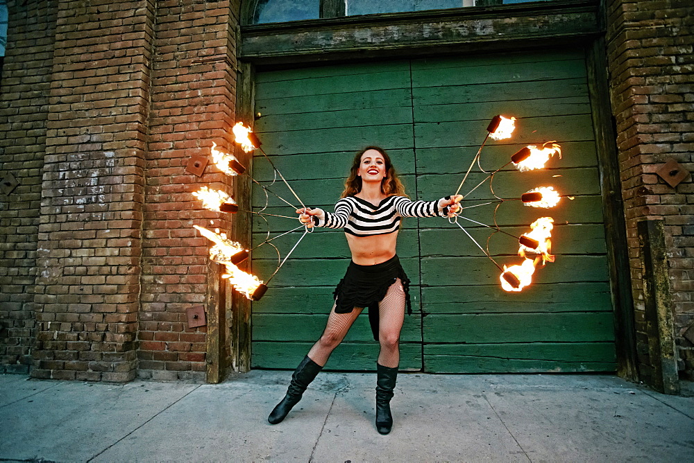 Caucasian woman juggling fire on city sidewalk