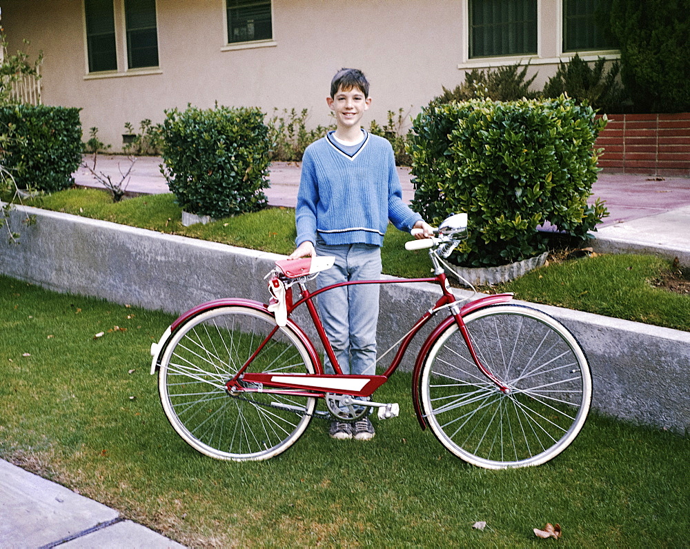 Portrait of smiling Caucasian boy posing with bicycle