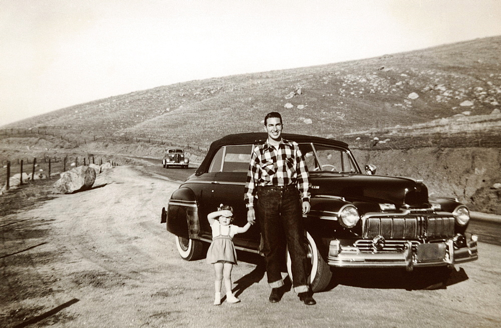 Portrait of Caucasian father and daughter posing near vintage car