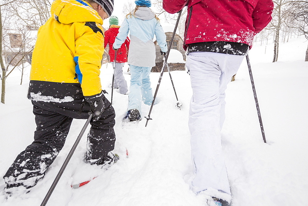 Rear view of Caucasian family snowshoeing