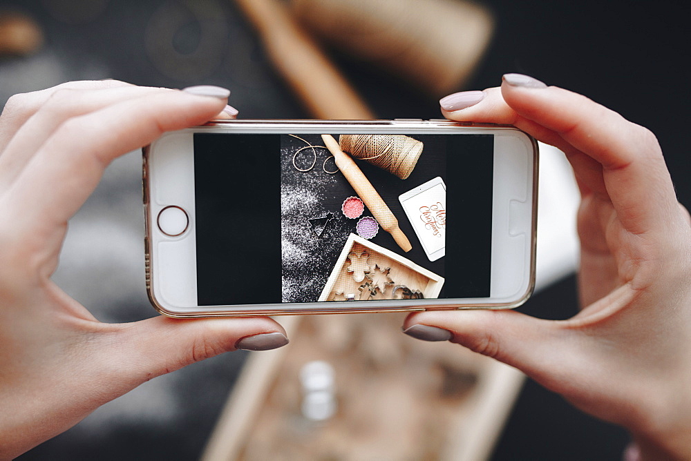 Hands of Caucasian woman photographing baking supplies