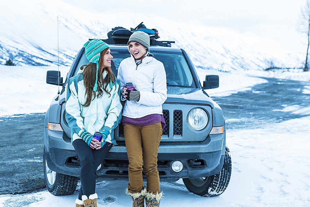 Caucasian women laughing near car in winter