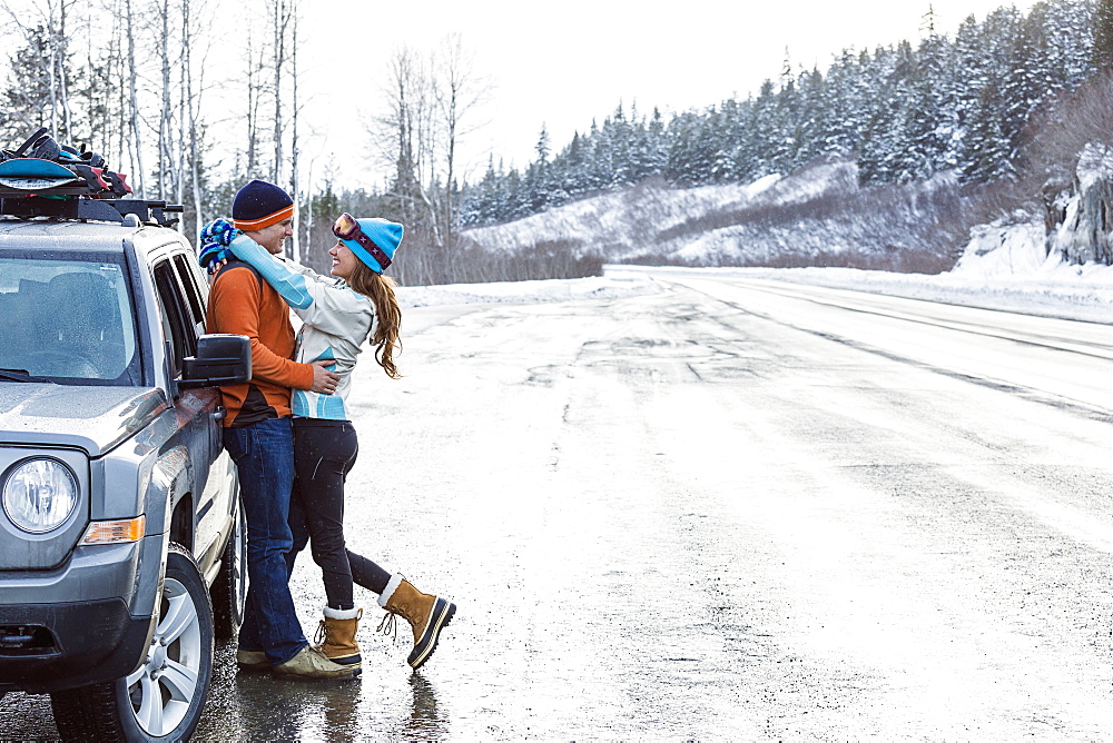 Caucasian couple hugging near car in winter