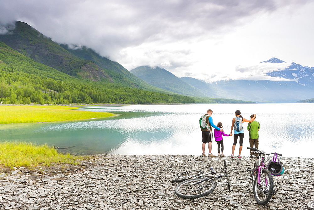 Couple with son and daughter riding bicycles near lake