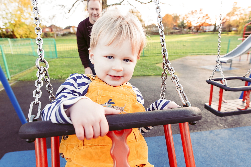 Caucasian father pushing son on swing