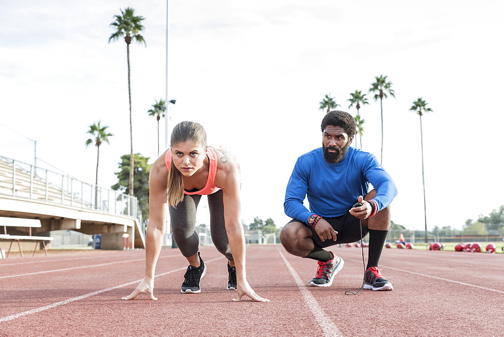 Man timing woman on track in starting position