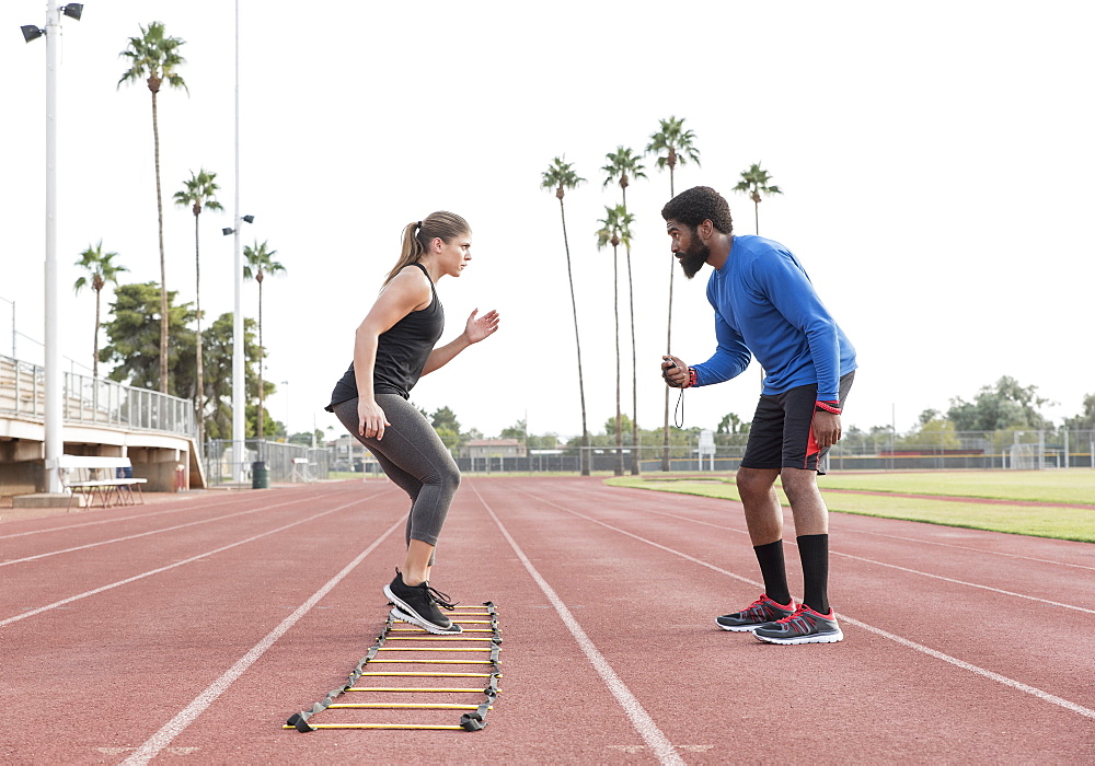 Trainer watching woman running ladder