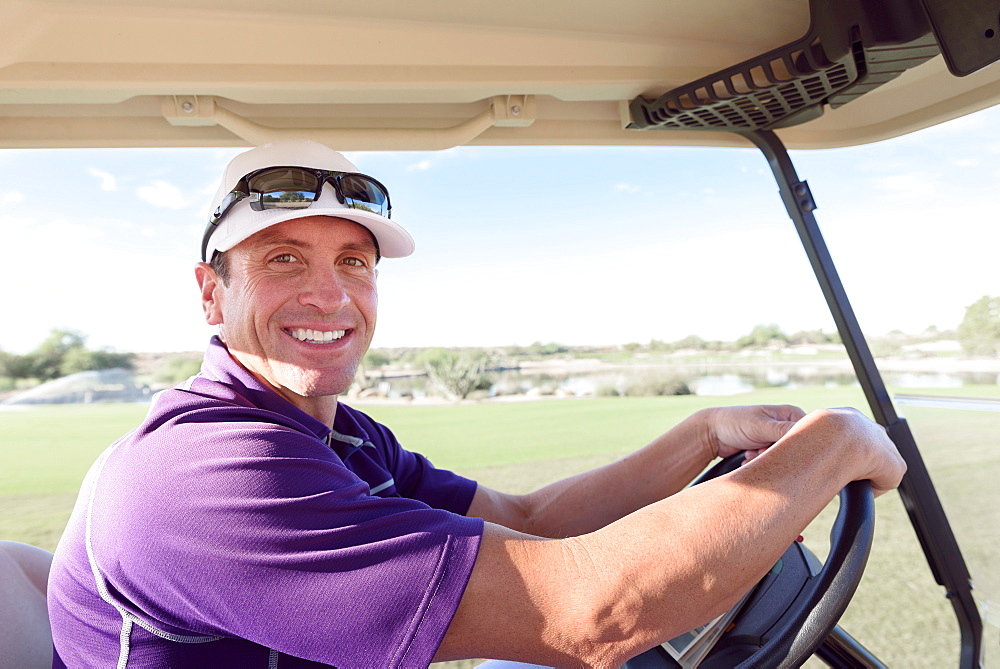 Portrait of smiling Hispanic man driving golf cart