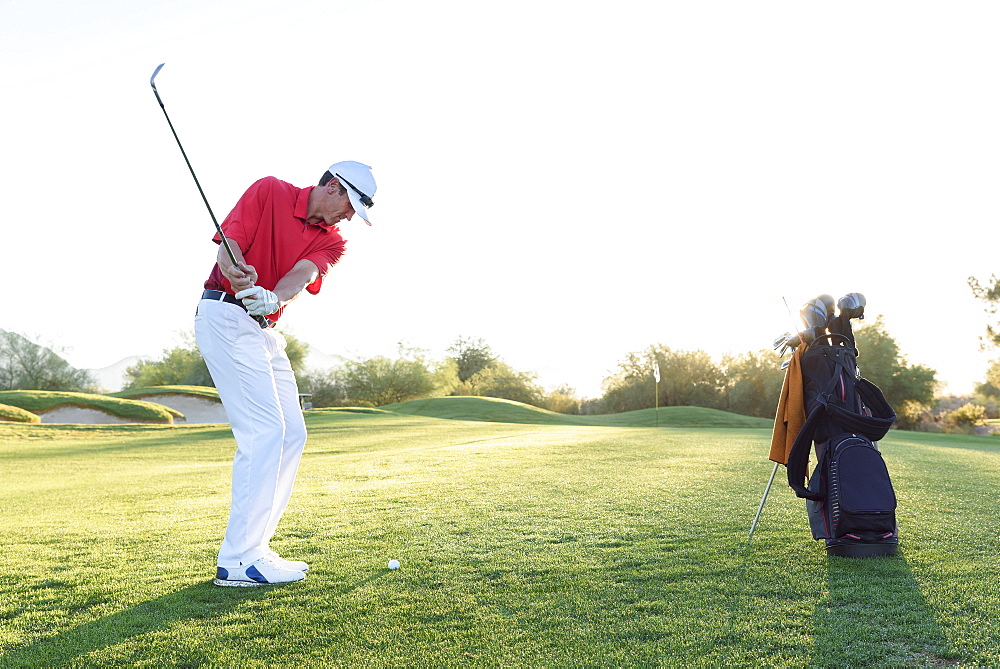 Hispanic man hitting ball on golf course