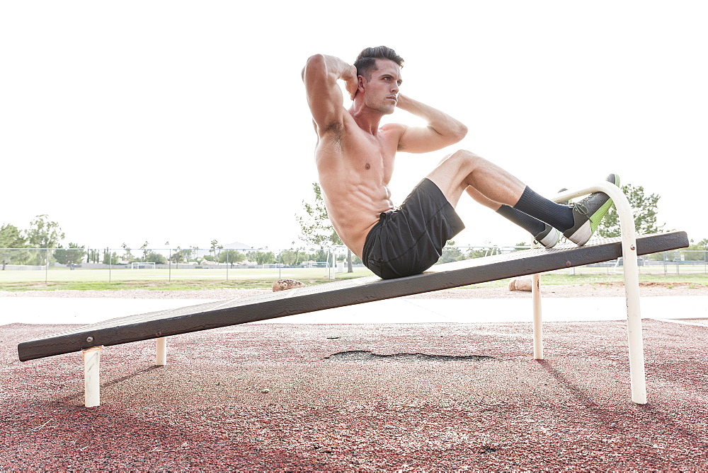 Caucasian man doing sit-ups outdoors