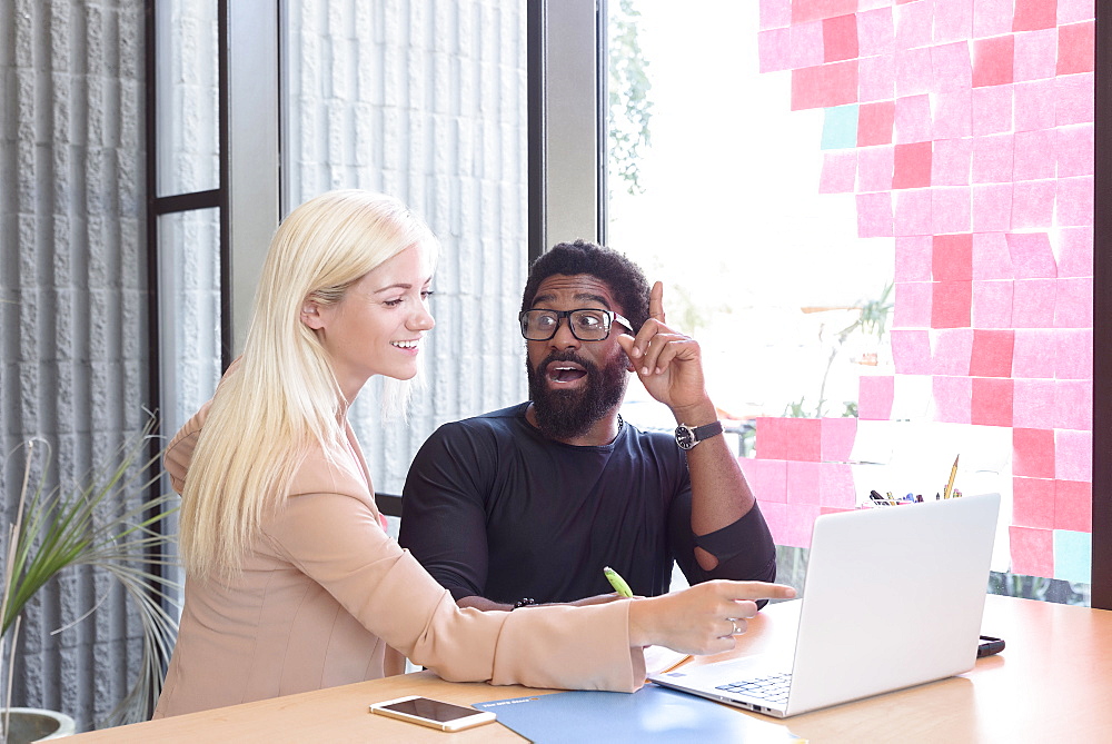 Creative business people using laptop at table