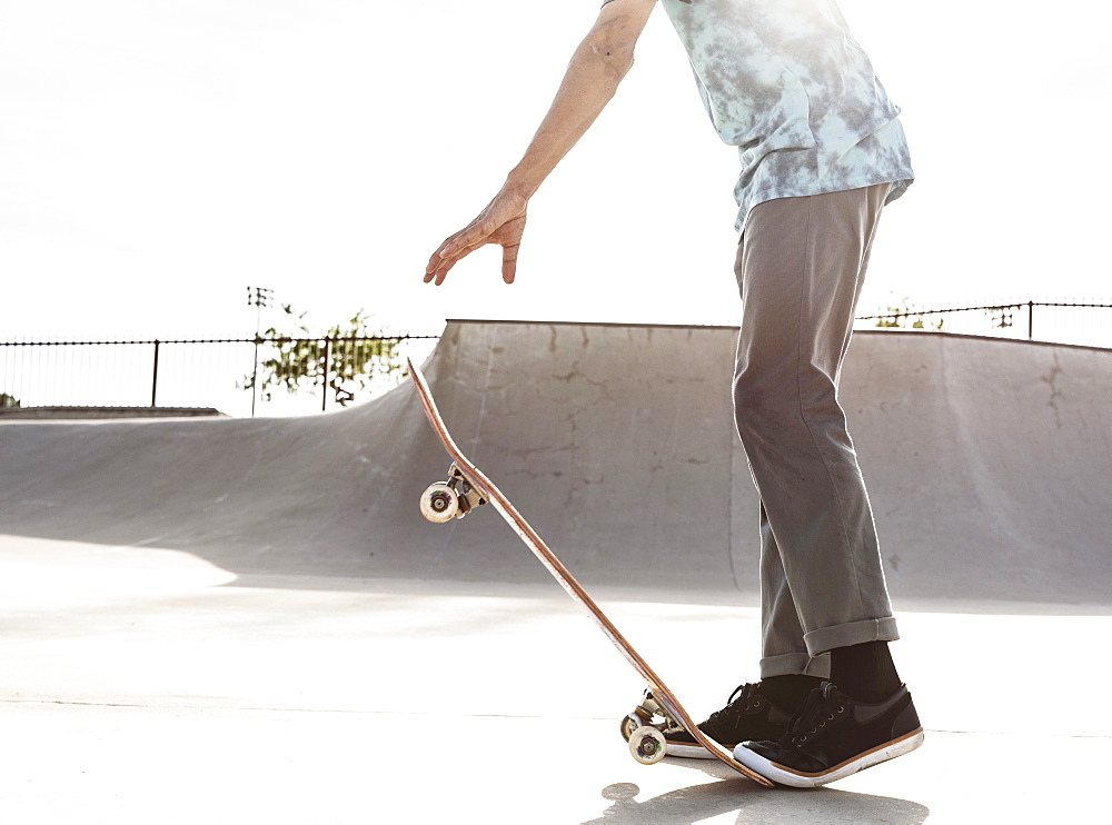 Hispanic man stepping on tail of skateboard