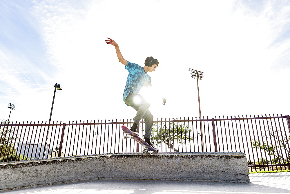 Hispanic man riding skateboard in skate park