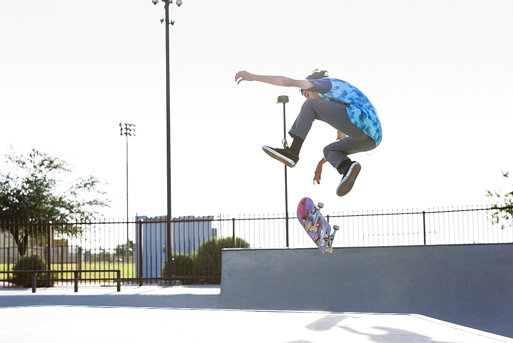 Hispanic man performing mid-air trick on skateboard