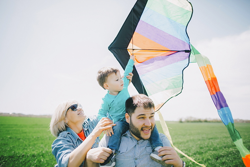 Caucasian boy flying kite with father and grandmother