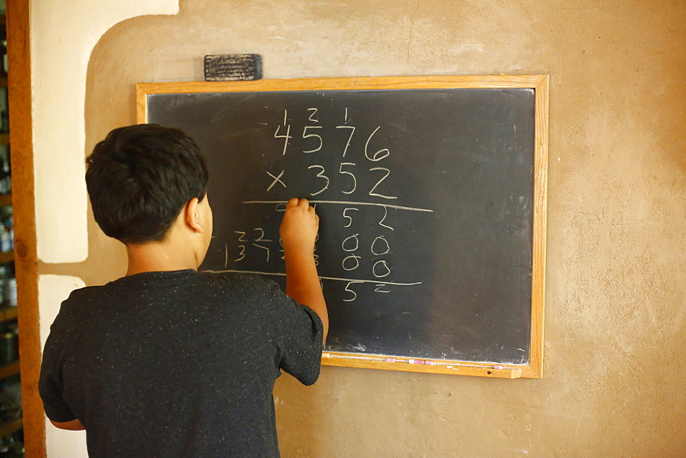 Native American boy solving equation on blackboard