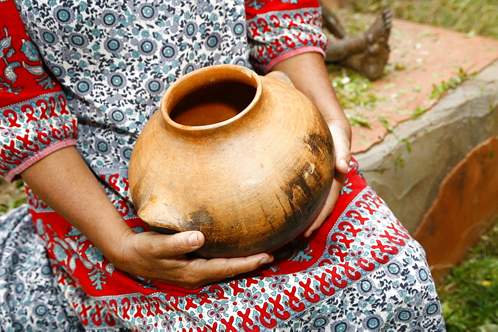 Woman sitting and holding clay pot