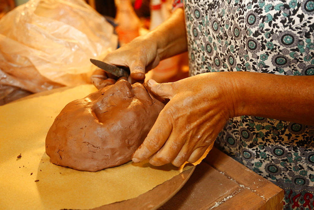 Mixed race woman shaping clay mask in art studio