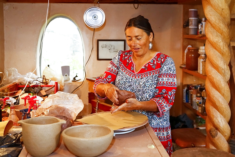 Mixed race woman shaping clay in art studio