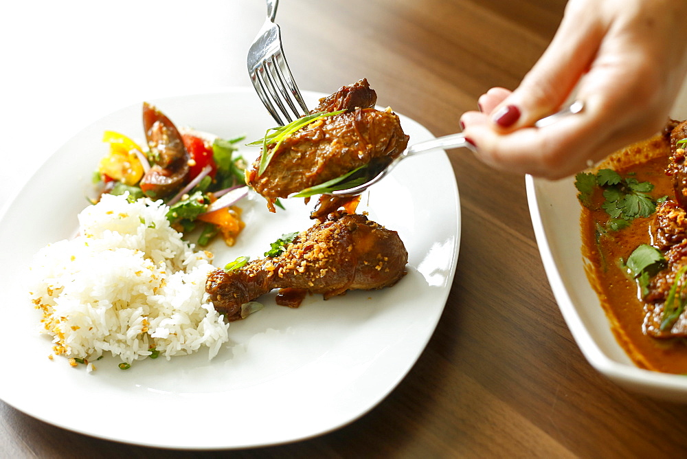 Woman holding meat over plate with fork and spoon