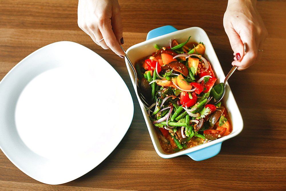 Hands of woman mixing salad