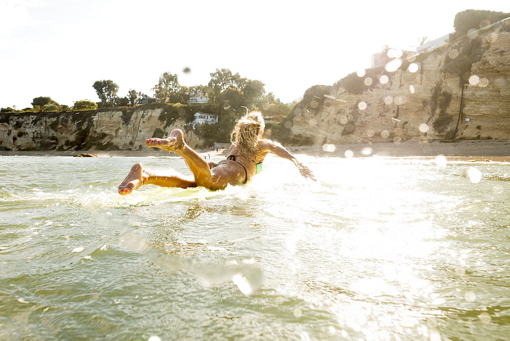 Caucasian woman paddling on surfboard in ocean