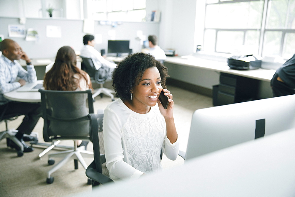 Businesswoman talking on cell phone in office