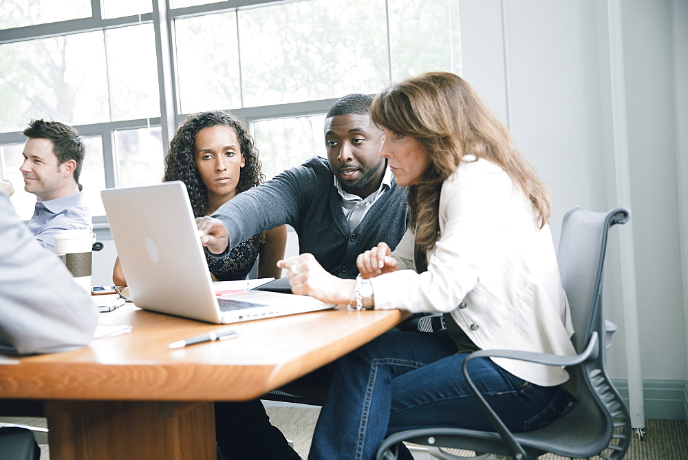 Business people using laptop in meeting