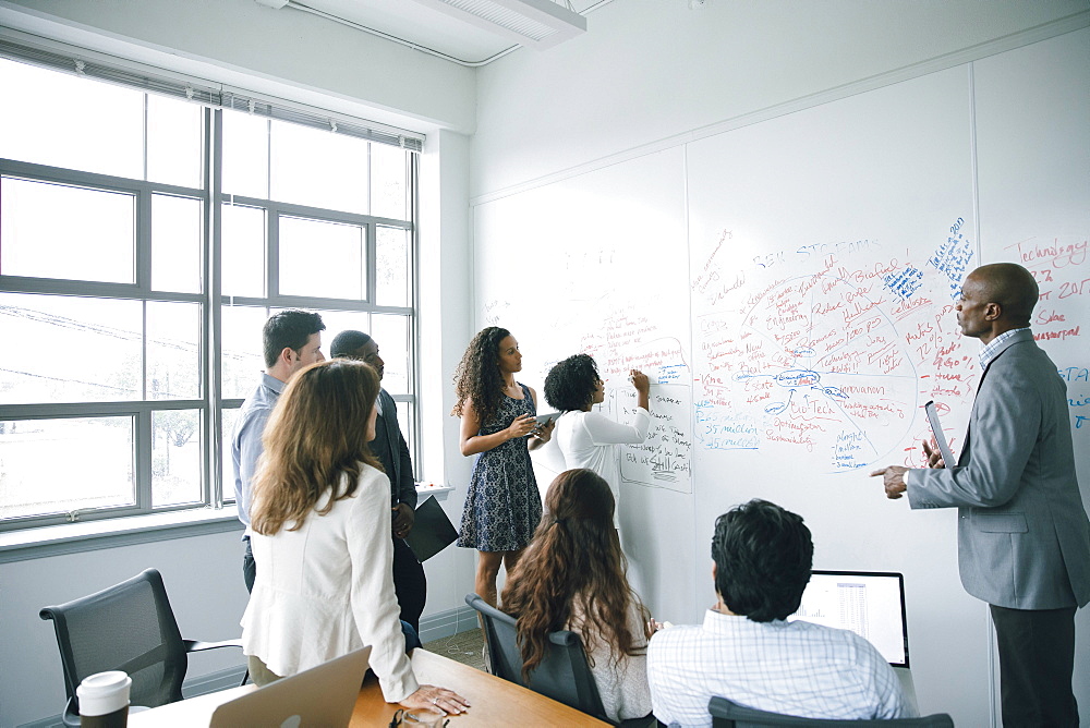 Businesswoman writing on whiteboard in meeting