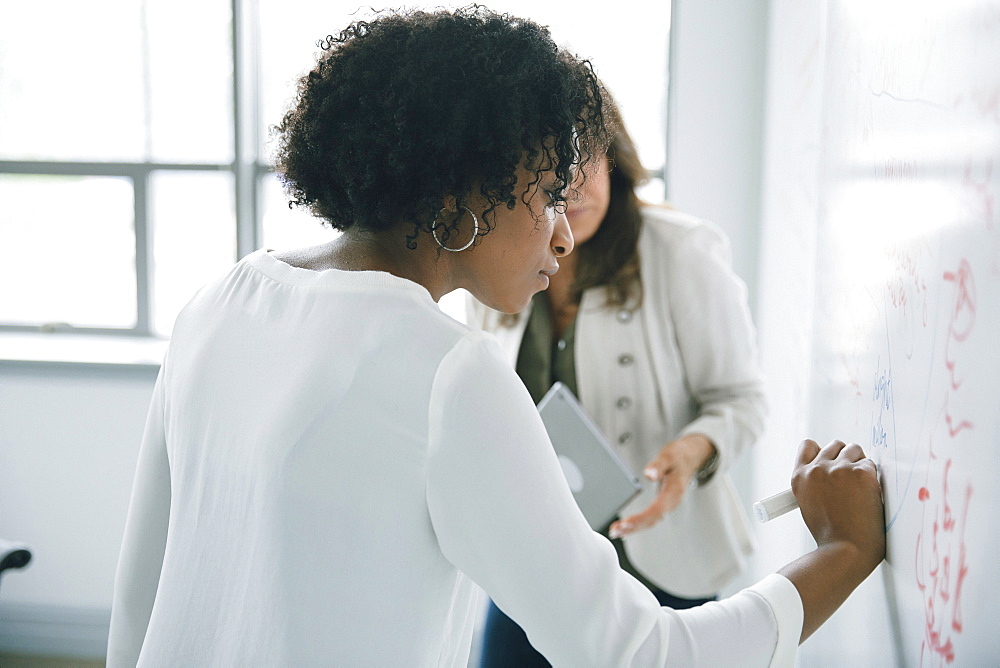 Businesswoman writing on whiteboard in meeting