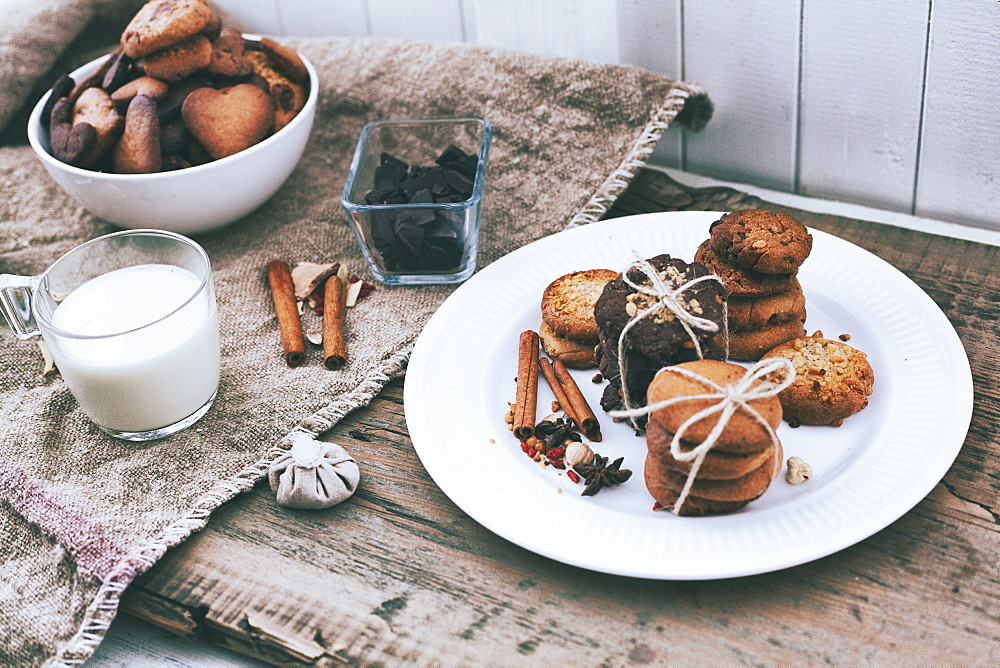 Bundles of cookies tied with string on plate near ingredients