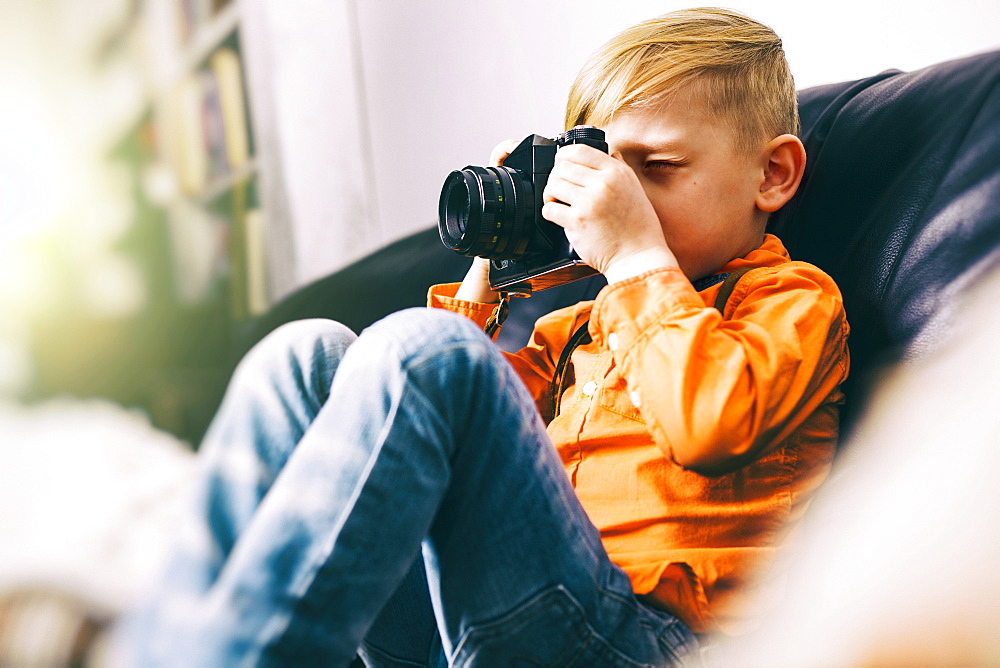 Caucasian boy sitting on sofa using camera