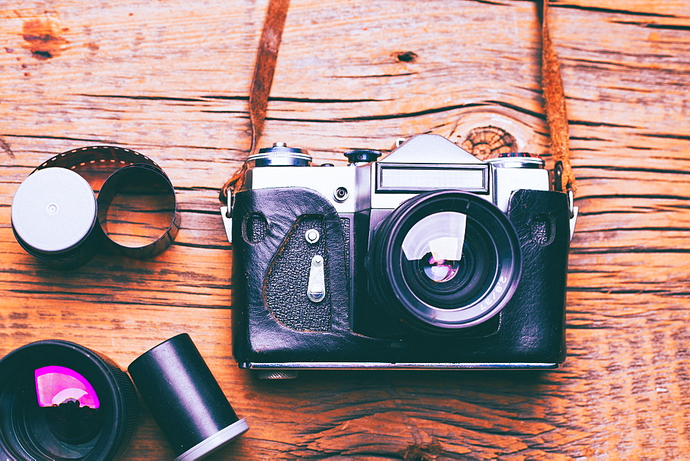 Camera with lens and film on wooden table