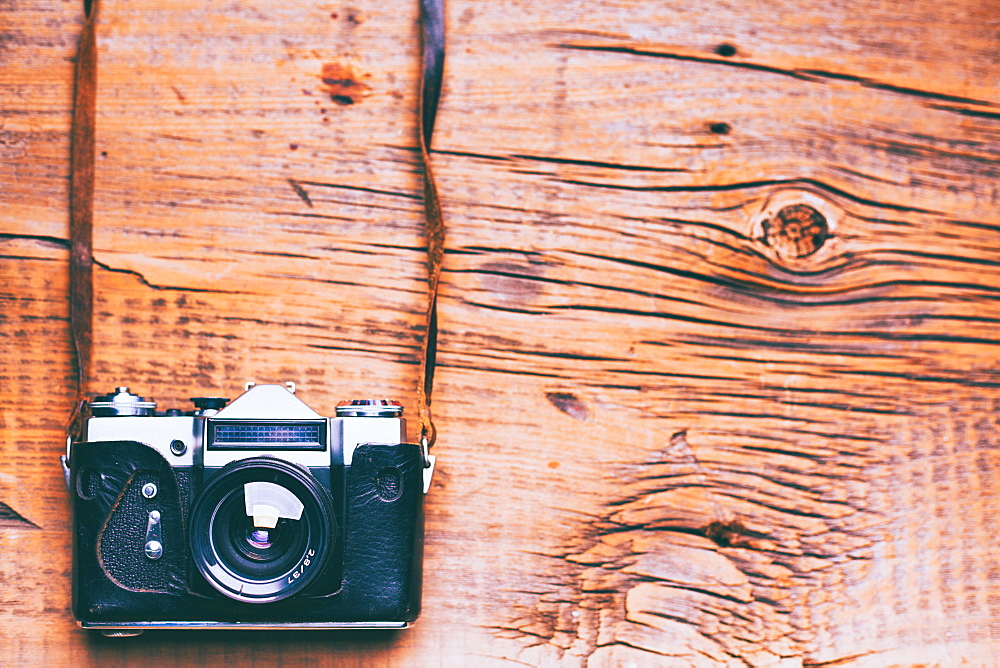 Camera and strap on wooden table