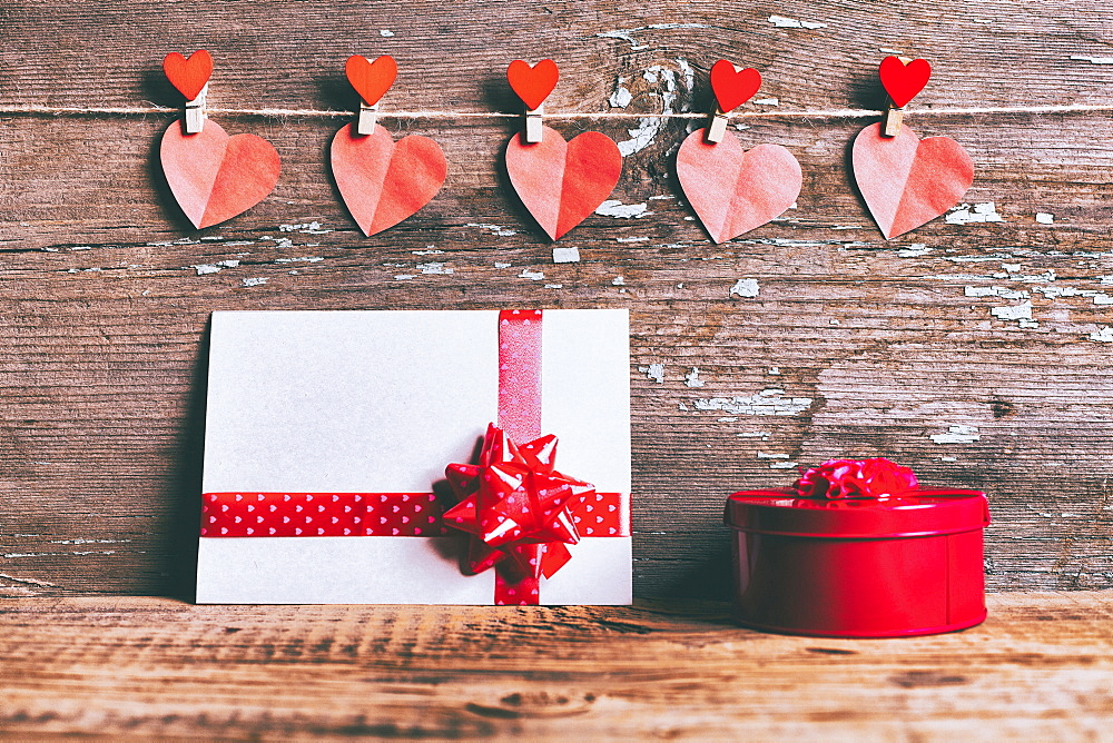 Valentine hearts hanging on string above gift box and card