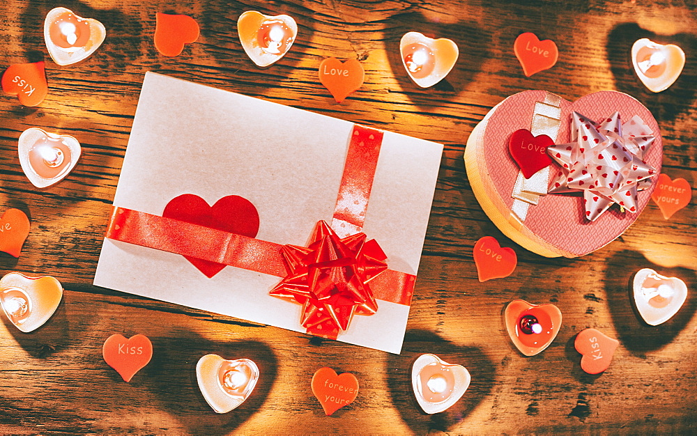 Valentine candles burning on table with gift box and card