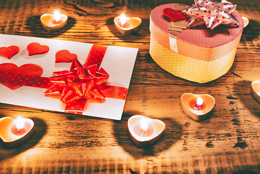 Valentine candles burning on table with gift box and card