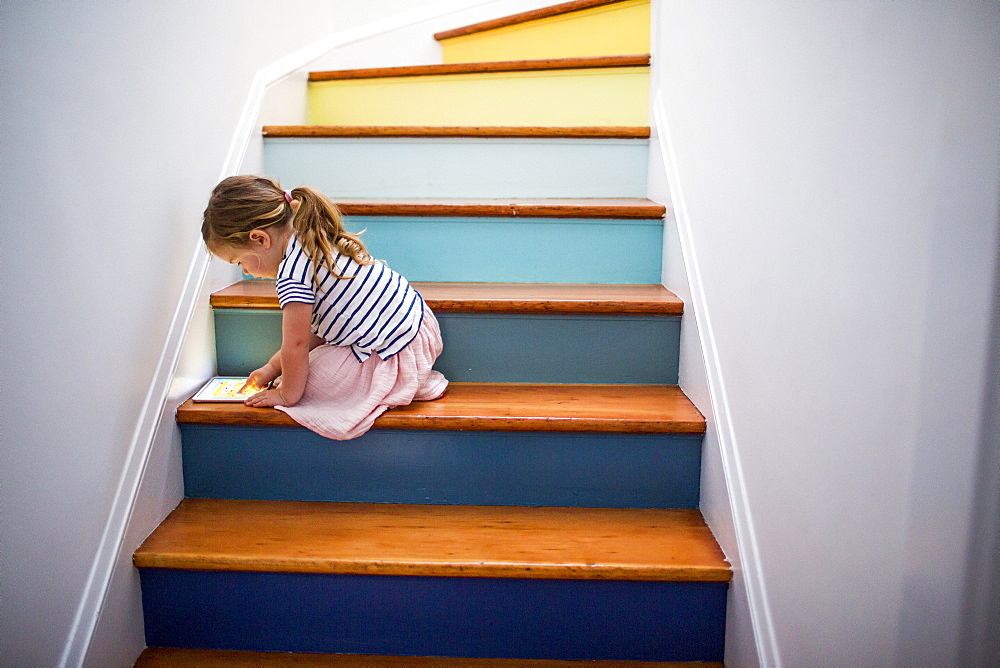 Caucasian girl using digital tablet on multicolor staircase