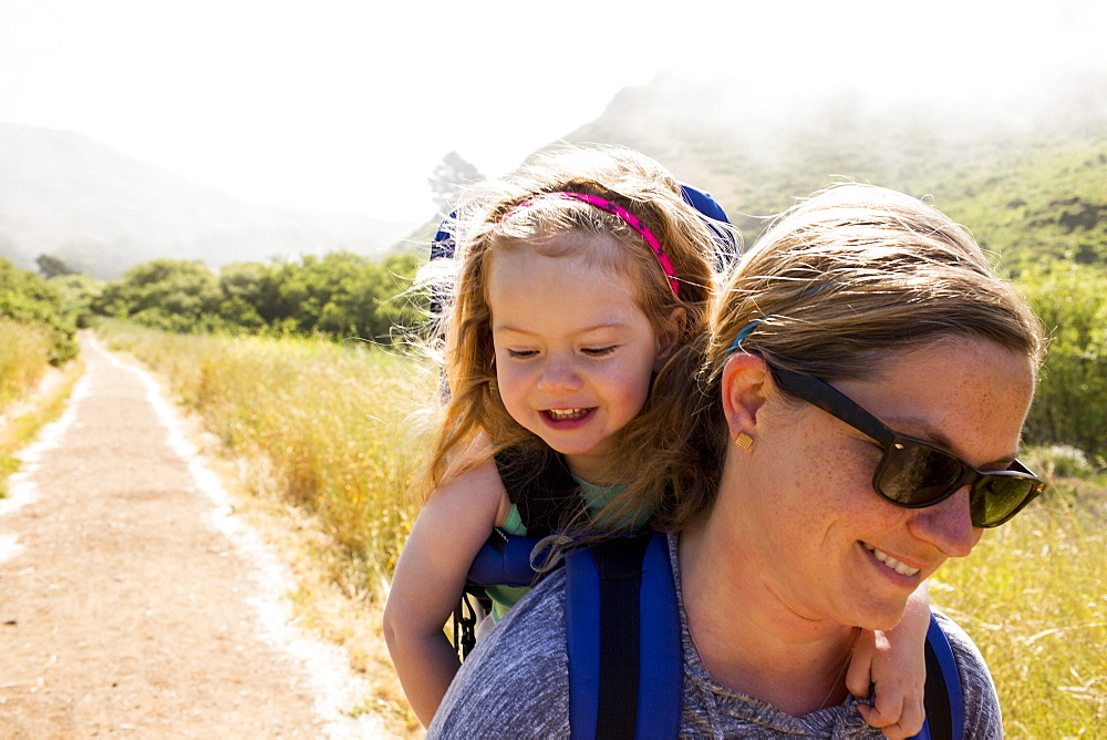 Caucasian mother carrying daughter while hiking