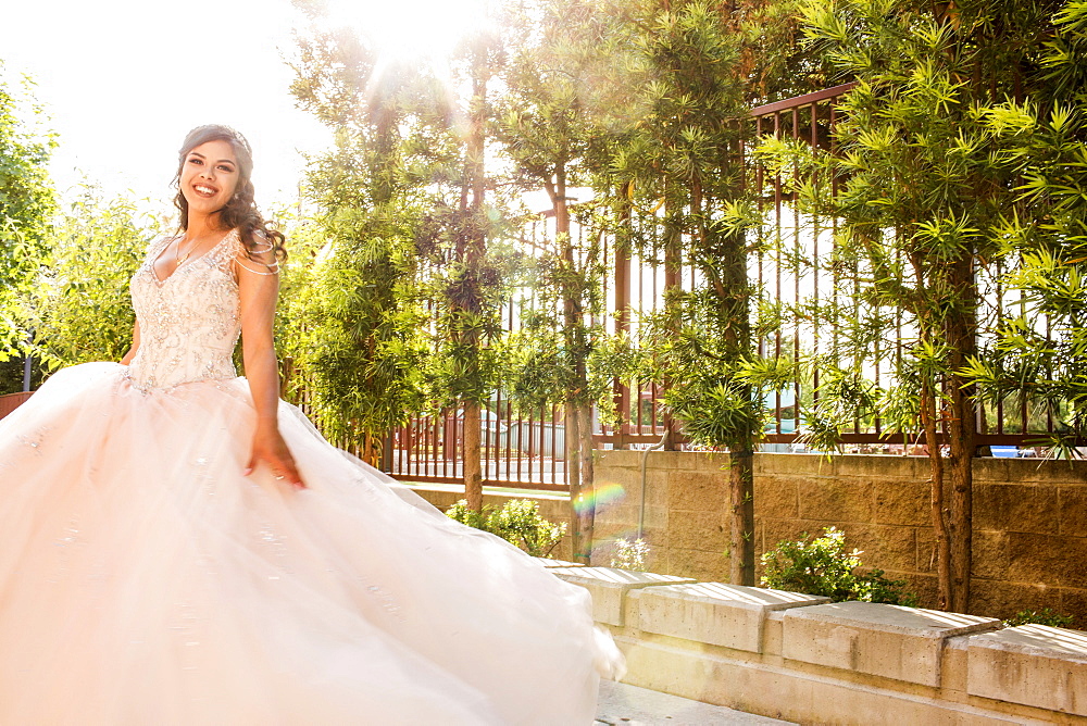 Smiling Hispanic girls wearing gown in park