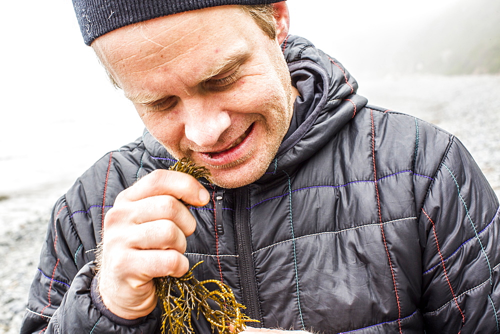 Caucasian man biting seaweed near ocean