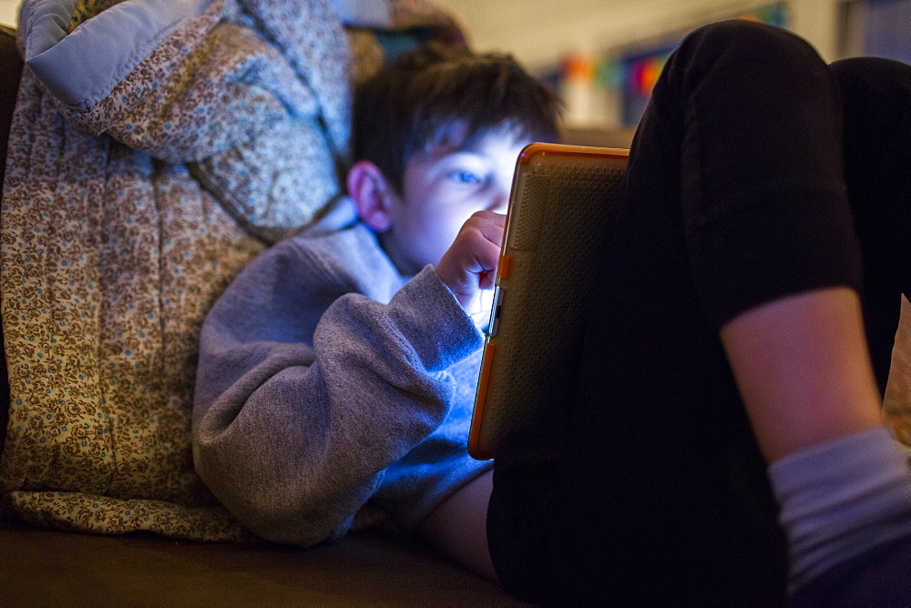 Mixed Race boy using digital tablet at night