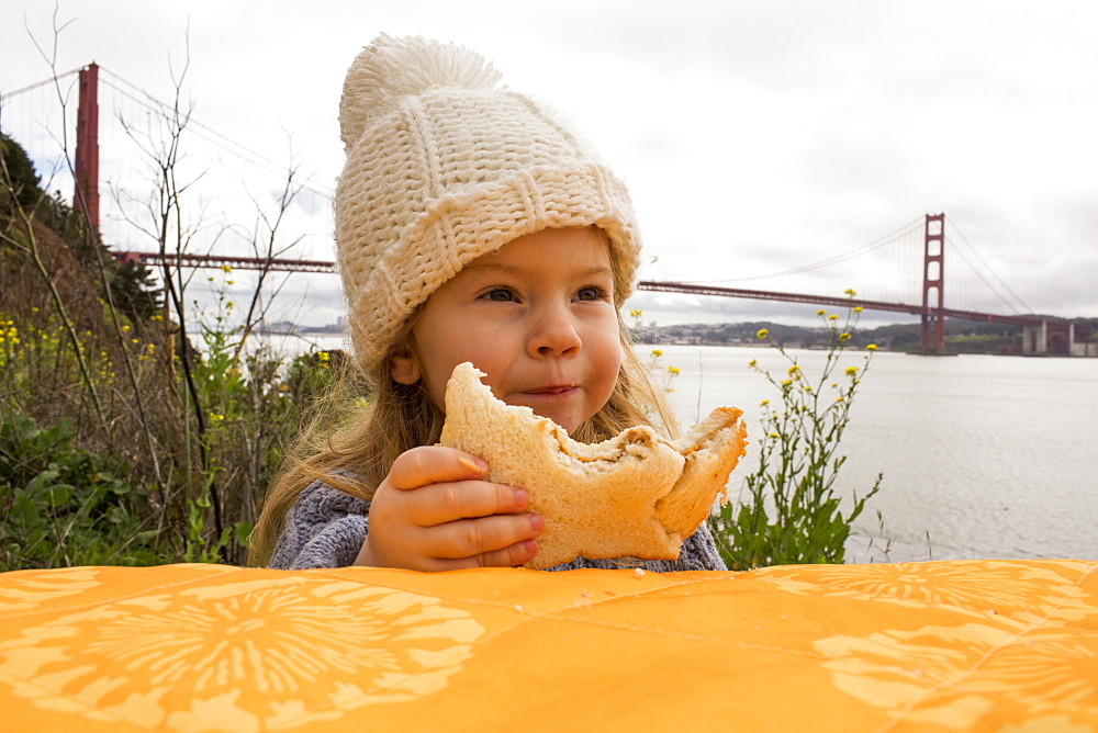 Caucasian girl eating sandwich outdoors