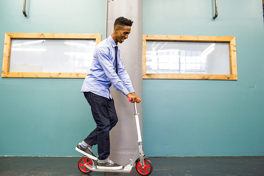 Black man riding scooter indoors