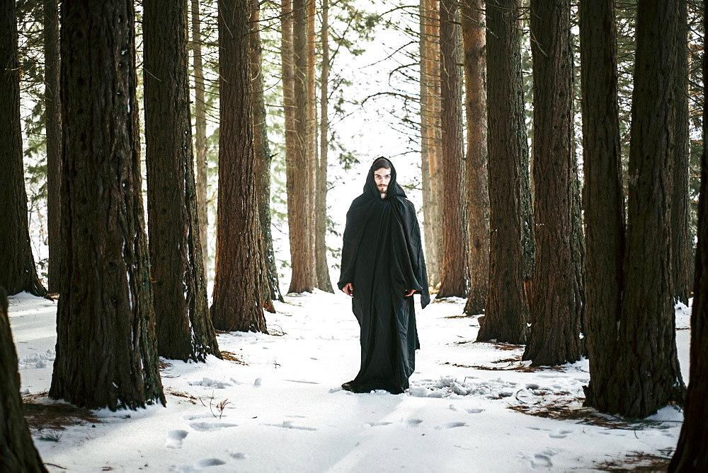 Caucasian man with beard wearing robe in forest during winter