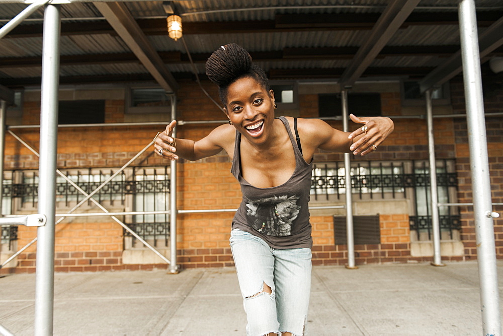 Smiling African American woman dancing under scaffolding